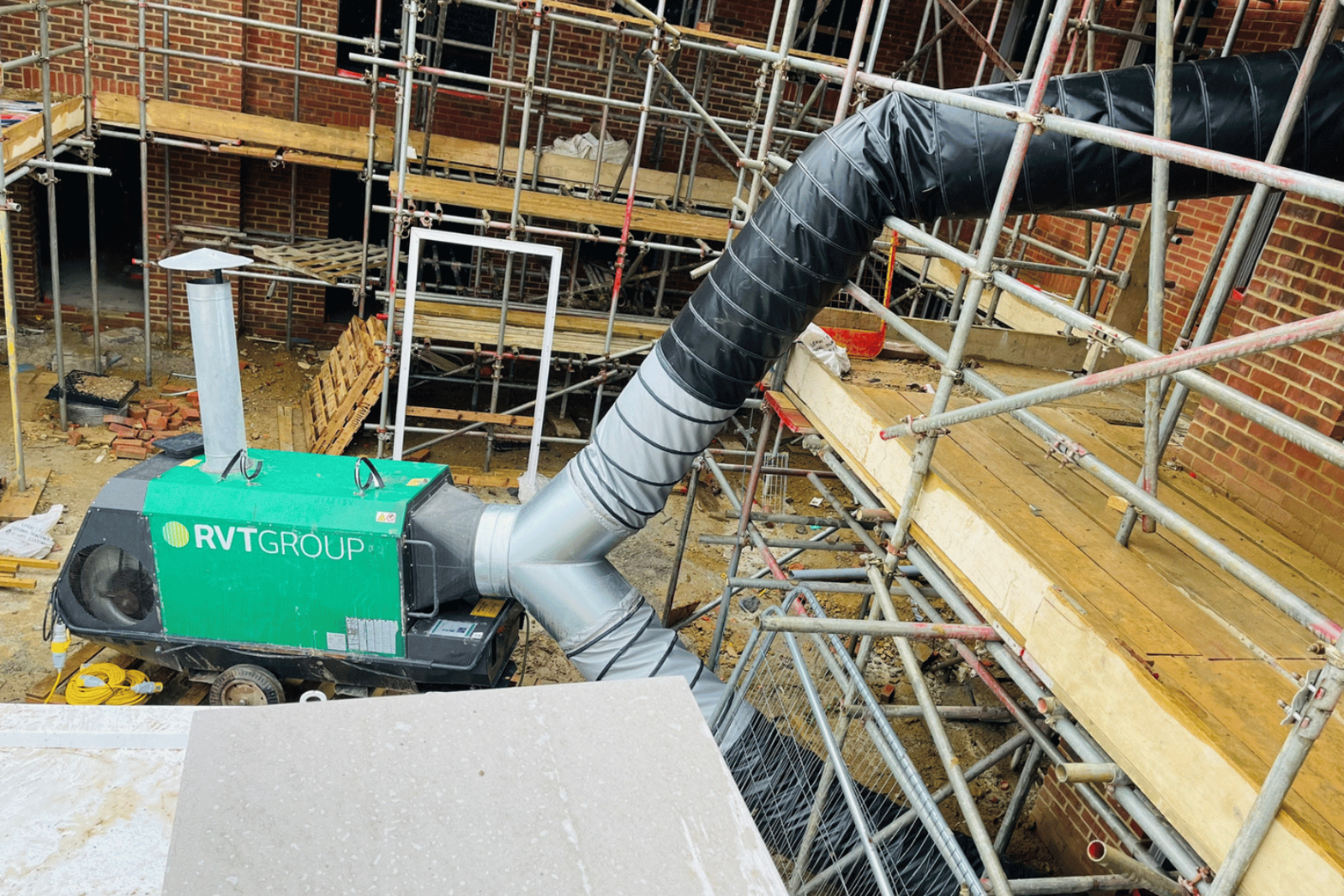 Climex Indirect Oil-Fired Heater from the side with a splitter attached and two lines of ducting going into the bottom floor and second floor of a live new build project