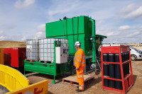 EnviroHub-TU02-dosing-skid-treatment-tank-and-lamella-settlement-tank-on-an-Infrastructure-site-with-a-worker-in-full-orange-overalls-tending-to-it