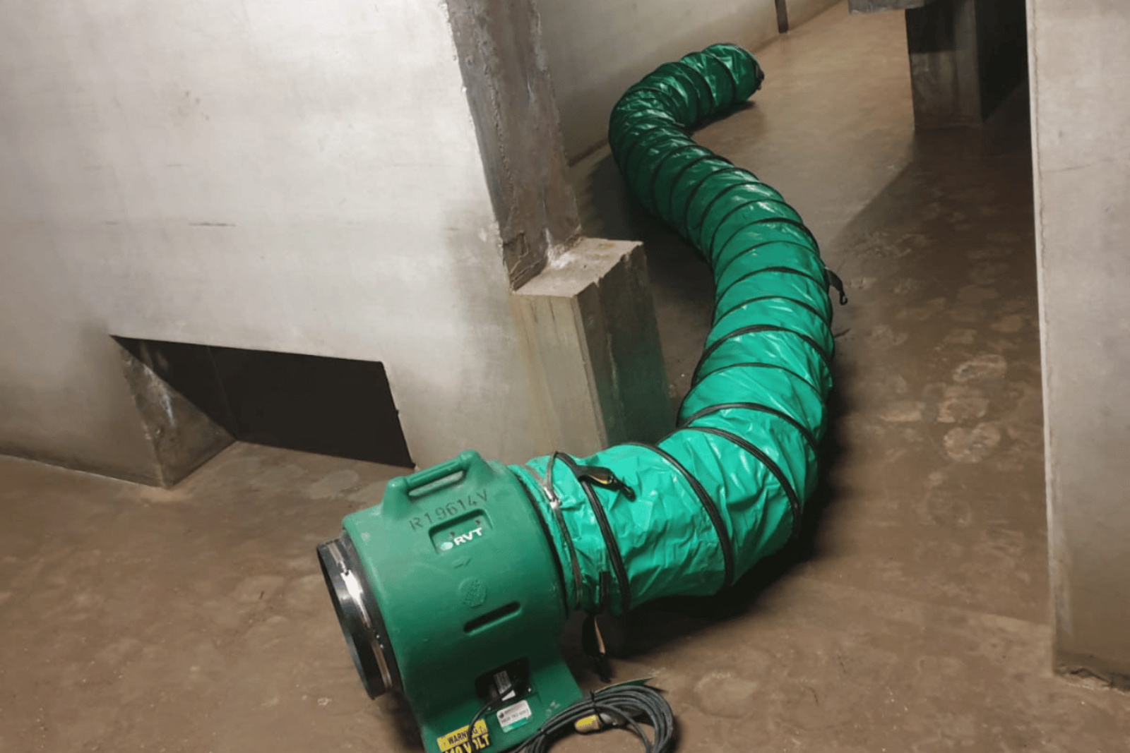 Climex Air Distribution Kit 300 set up in a doorway with a wet floor with damp footsteps in them and wet, fresh plaster