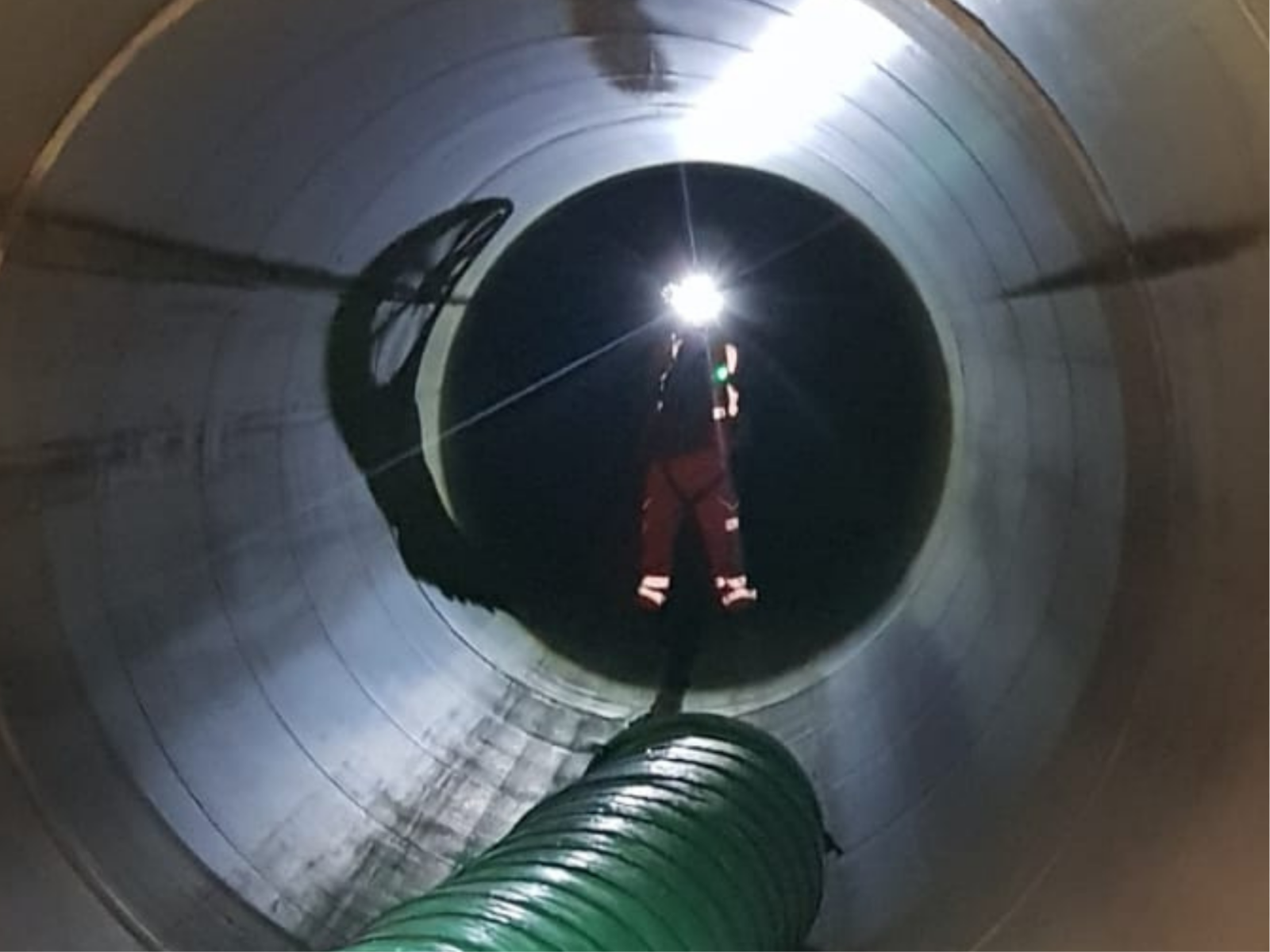 Worker shining light from a Hand Torch down a tunnel
