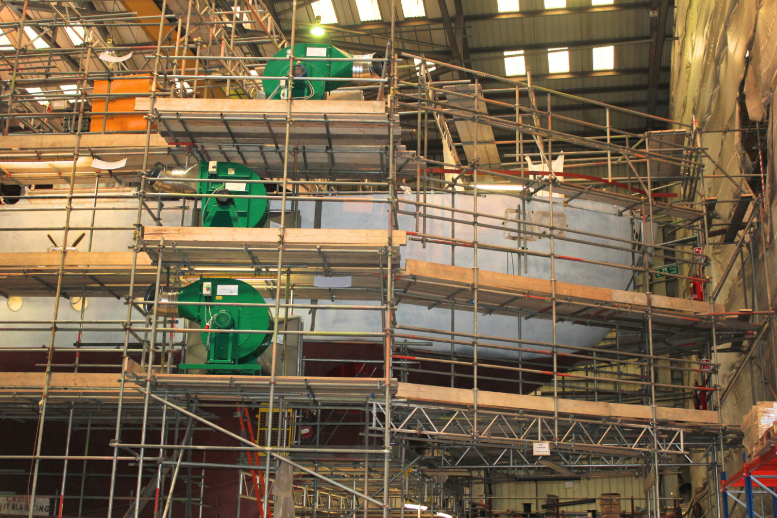 3 VENTEX Centrifugal Fan 450S units spread across 3 floors of scaffolding whilst works take place on a ship behind the scaffolding structure