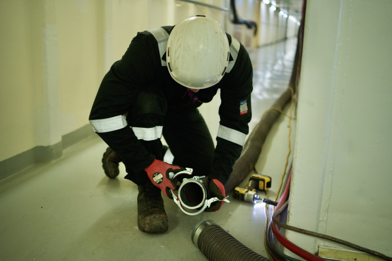 Engineer installing ducting within the ship.
