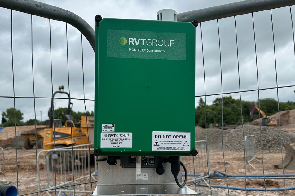 Dust monitor in the foreground with construction work and machinery in the background