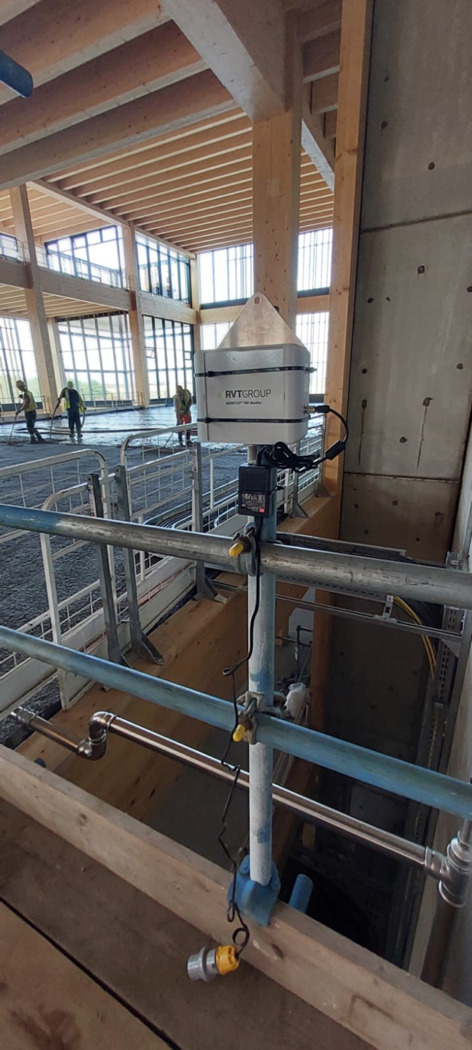 Monitex Temperature and Humidity Monitor in place whilst workers pour concrete flooring in place in the background