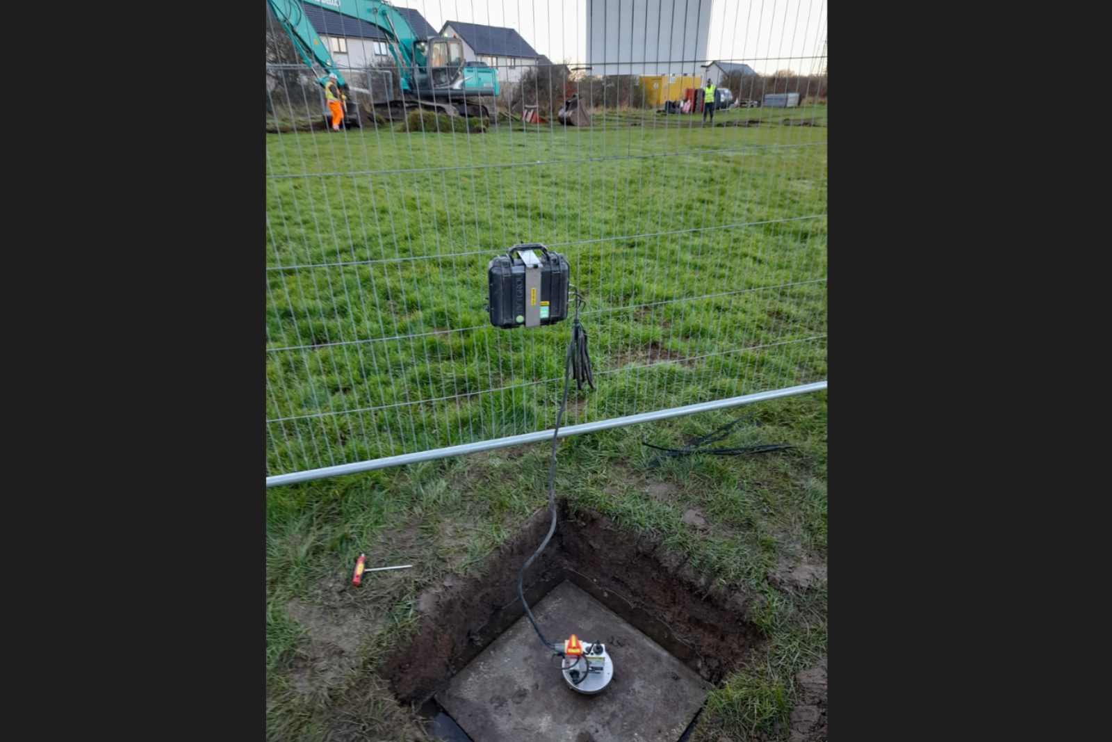 Monitex vibration monitor in the foreground whilst excavation takes place on a field in the background