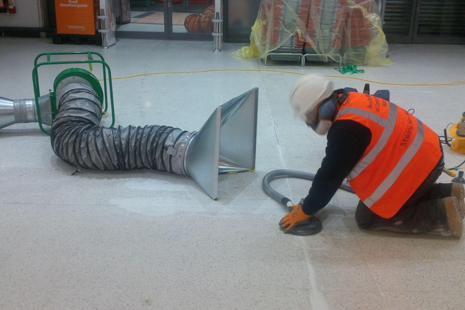 VENTEX® Centrifugal Fan 200P in place on the floor whilst a worker in a hi-vis vest and face mask sands the floor nearby