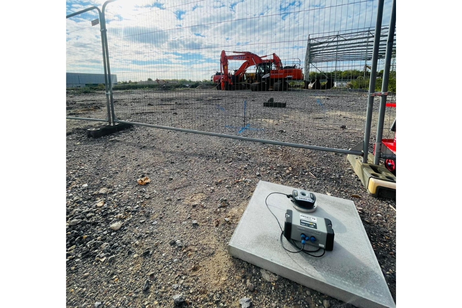 Vibration monitor in the foreground and heavy machinery in the background