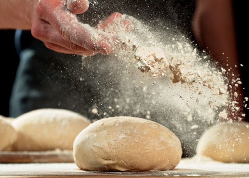 Flour dust being shown in mans hand across bread rolls