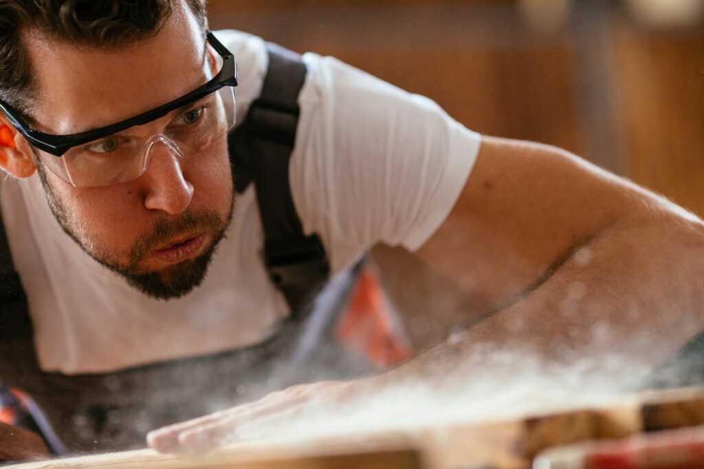 man blowing away wood dust